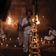 A man dressed all in white conducts a ritual in a space filled with candles in a scene from The Medium.